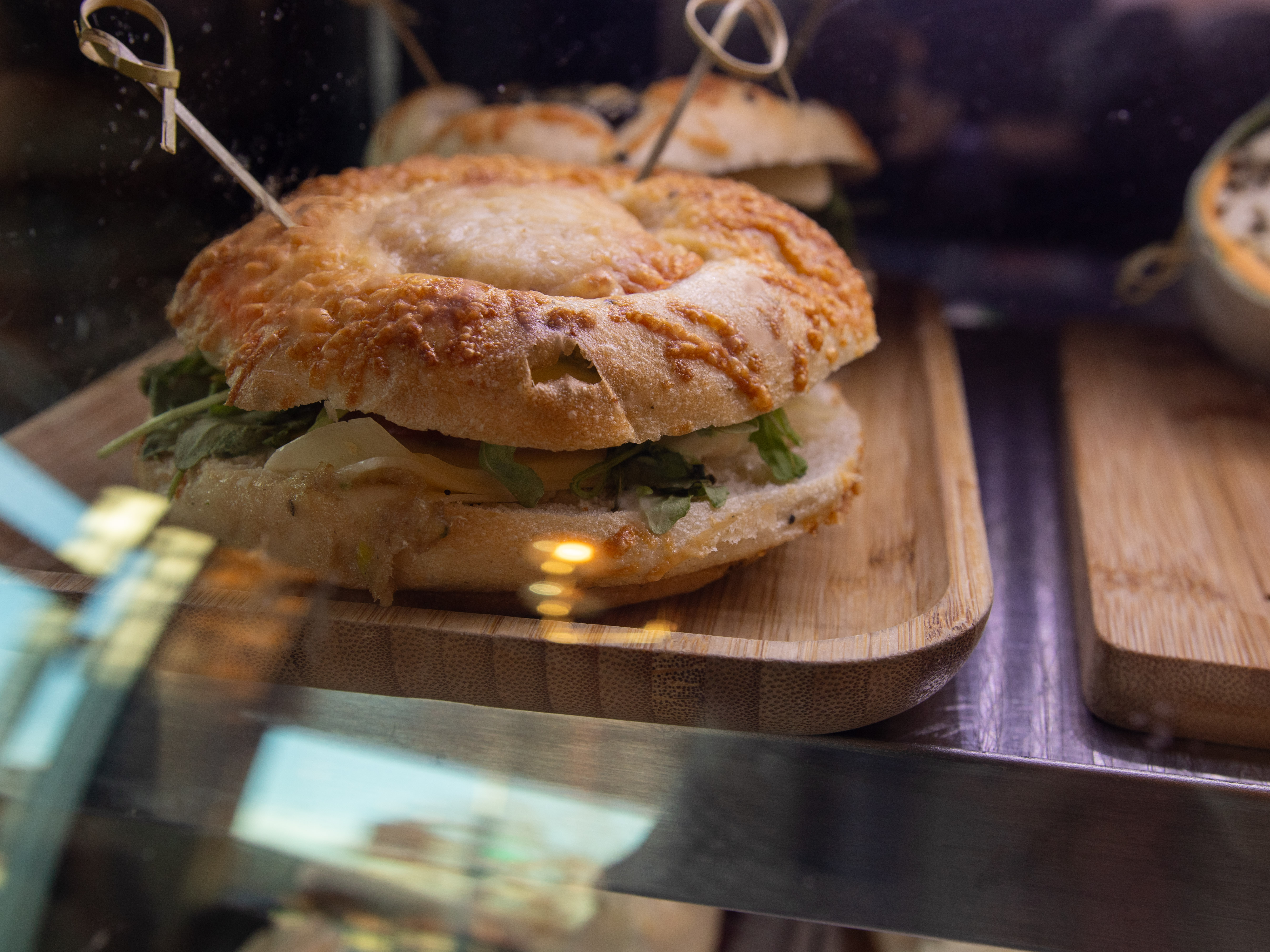 A close-up of a freshly made sandwich with a golden-brown crust and green lettuce on a wooden serving board.